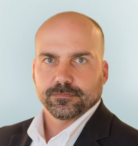 Headshot of Christian V. Kuhlen, MD, JD General Counsel on light sage background